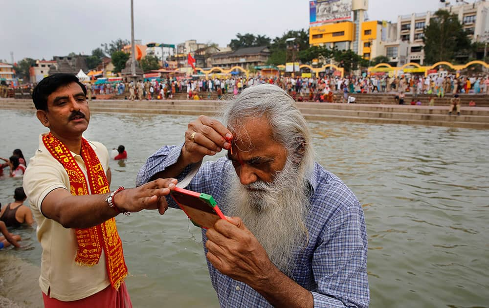 An elderly Hindu devotee applies a vermilion mark on his forehead after a holy dip on the second 'shahi snaan' or royal bath in the river Godavari during the ongoing Kumbh Mela, or Pitcher Festival, in Nasik, India.