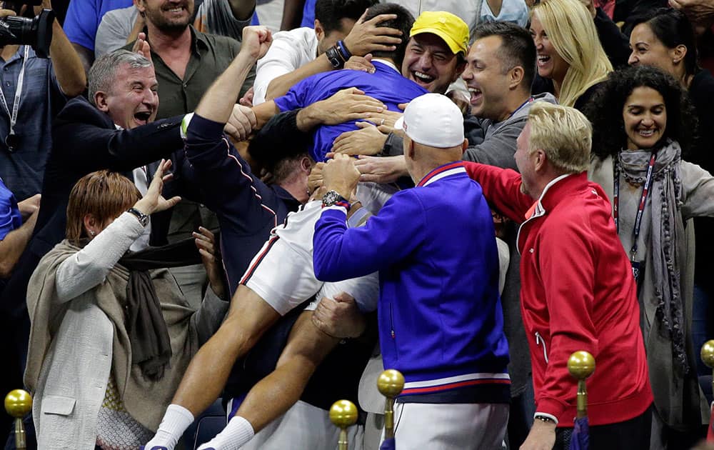 Novak Djokovic, of Serbia, is thronged by supporters after beating Roger Federer, of Switzerland, in the men's championship match of the U.S. Open tennis tournament in New York.