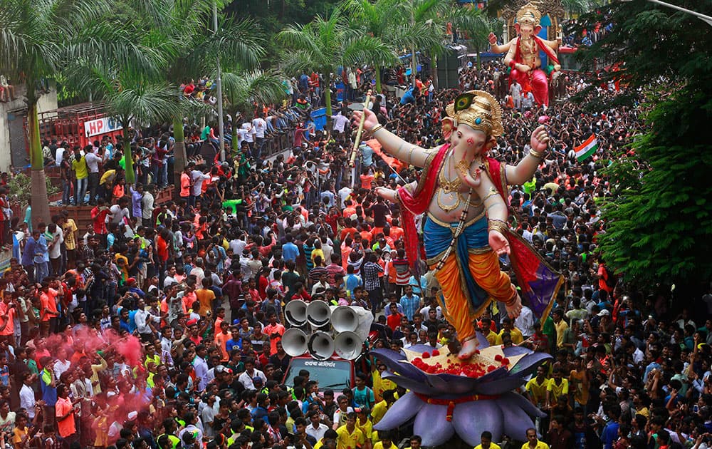 Devotees participate in a procession with large statues of Hindu god Ganesh in Mumbai.