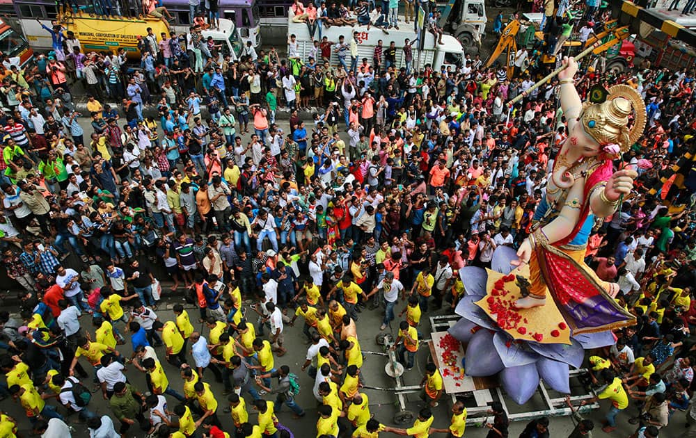 Devotees participate in a procession with large statues of Hindu god Ganesh in Mumbai.