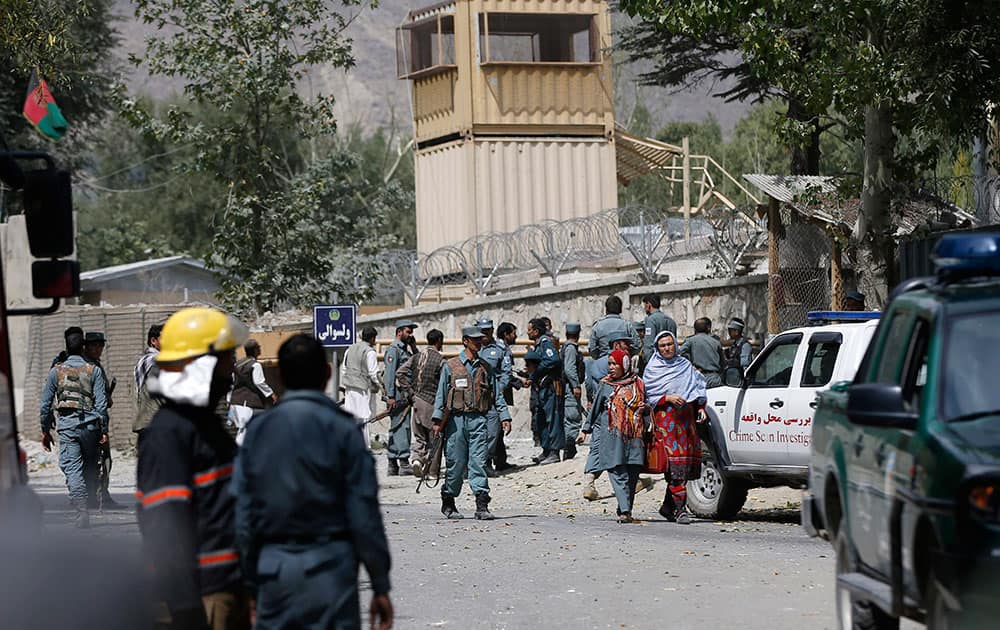 Afghan security forces walk near the main gate of Paghman district governor compound where a suicide car bomb attack happened in Paghman district of Kabul province, Afghanistan.