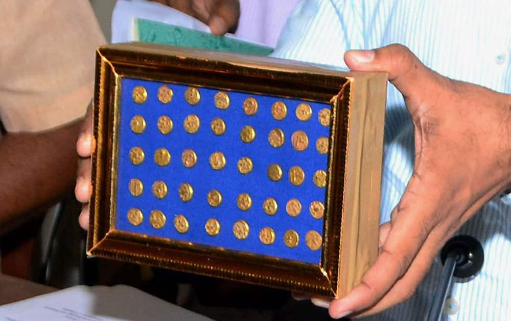 Officials of Department of Archaeology and Museums showing a treasure trove consisting of 40 ancient Gold Coins and a broken Brass container recovered from farm labouers by the police in Khammam district, in Hyderabad.