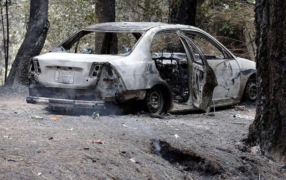 The charred remains of a car belonging to Leonard Neft, who has been missing since a wildfire tore through the area and destroyed his home days earlier, sits in the Anderson Springs area.