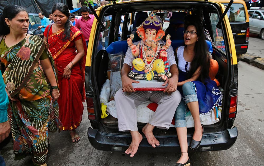 Devotees carry an idol of elephant-headed Hindu God Ganesha in the trunk of a taxi during Ganesh Chaturthi festival celebrations in Mumbai.