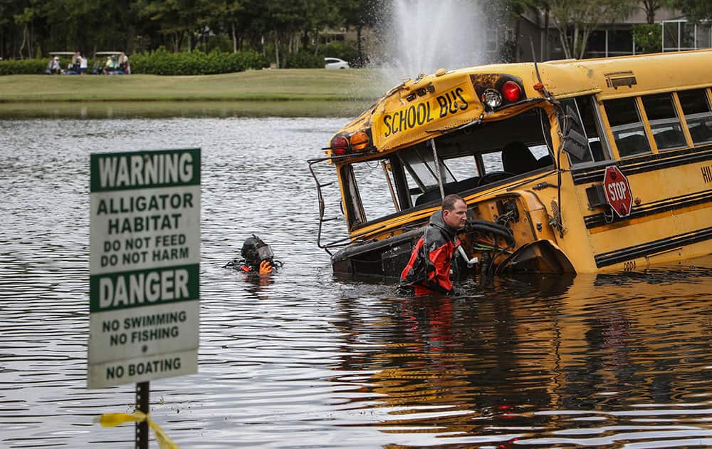 Sheriff divers inspect a flipped school bus that crashed into a pond.