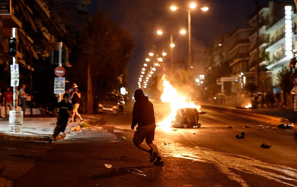 A masked protester runs in front of a burning garbage can as scuffles with the police broke out during an anti-fascist rally marking the death of Greek rap singer Pavlos Fyssas two years ago, at Keratsini suburb, in Athens.