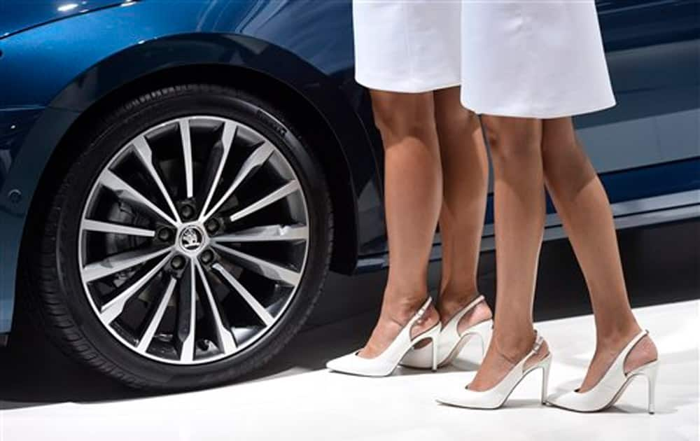 Two hostesses stand beside the wheel of a new Skoda Superb Combi on the first press day of the Frankfurt Auto Show IAA in Frankfurt, Germany.