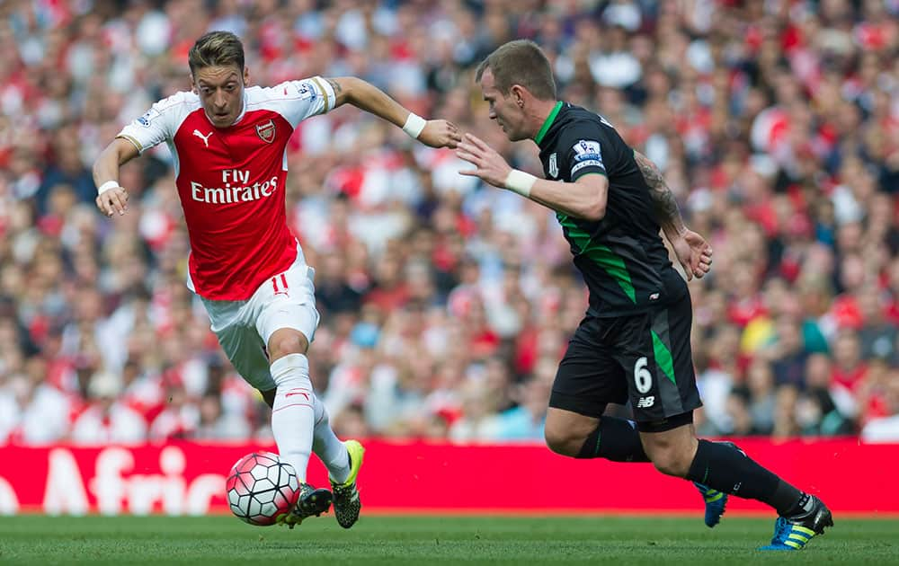 Arsenal's Mesut Özil, left, fights for the ball with Stoke City's Glenn Whelan, during their English Premier League soccer match between Arsenal and Stoke City, at Emirates Stadium, in London.