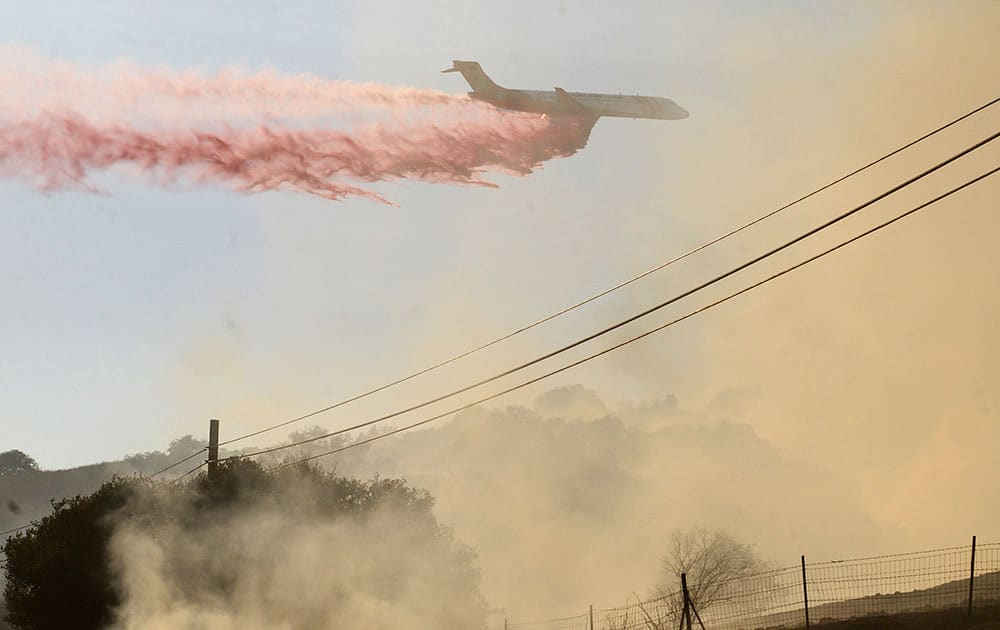 A plane drops fire retardant on a fire along Highway 68 east of Laureles Grade in rural Salinas, Calif.