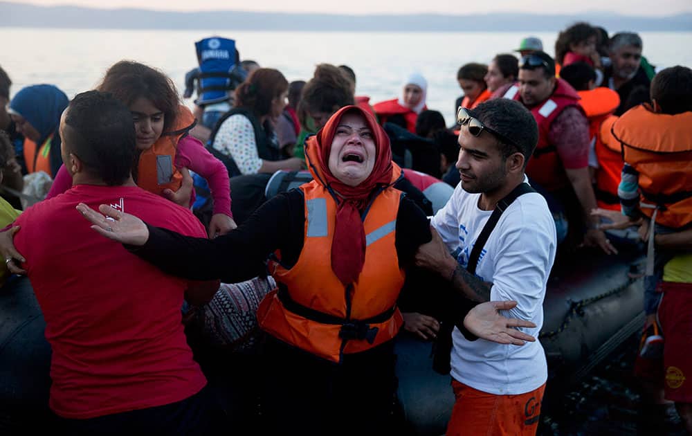 A woman reacts as she arrives aboard a dinghy after crossing from Turkey, to the island of Lesbos, Greece.