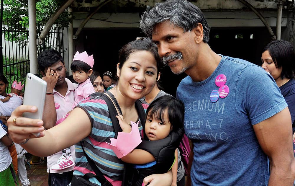 A woman along with her child takes selfie with model and Bollywood actor Milind Soman during an Awareness Campaign of Pinkathon Race to encourage an active lifestyle among women which will held on 27th September 2015 from Sonaram field in Guwahati.