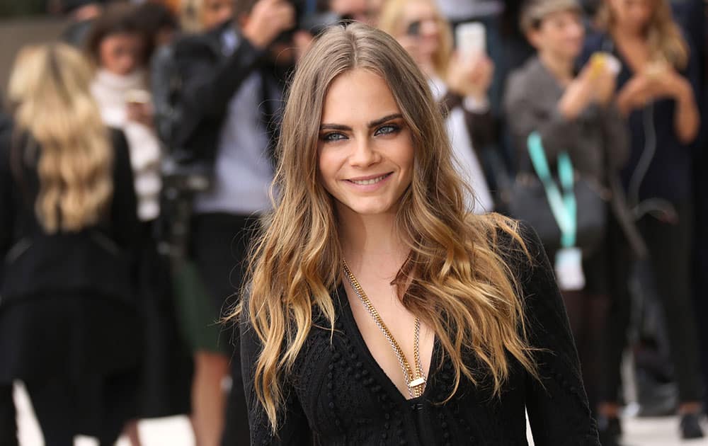 British model Cara Delevingne poses for photographs as she arrives for the Burberry Prorsum Womenswear Spring and Summer show in London.