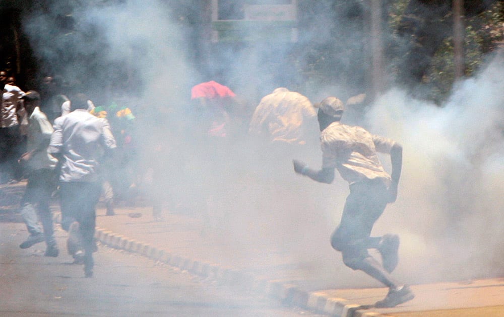 A university student run as police use tear gas to disperse students during demonstration in Nairobi, Kenya.