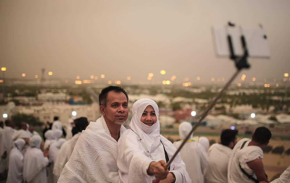 A Muslim pilgrim couple take a selfie on a rocky hill called the Mountain of Mercy, on the Plain of Arafat, near the holy city of Mecca, Saudi Arabia.