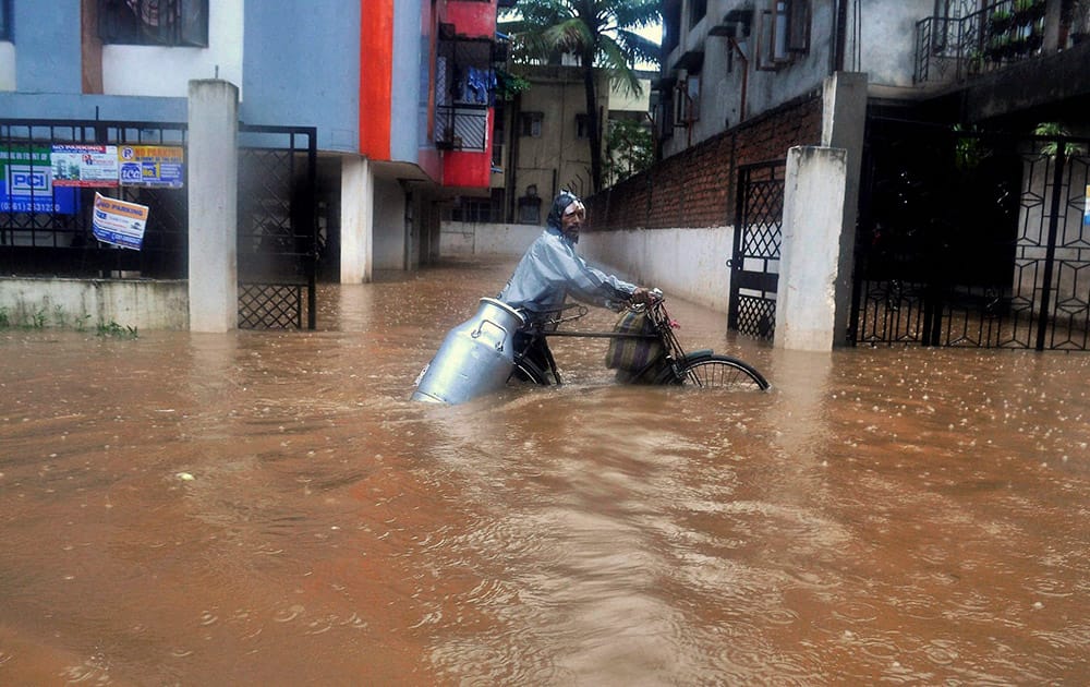 A milk vendor wades through a waterlogged street at Anil Nagar in Guwahati.