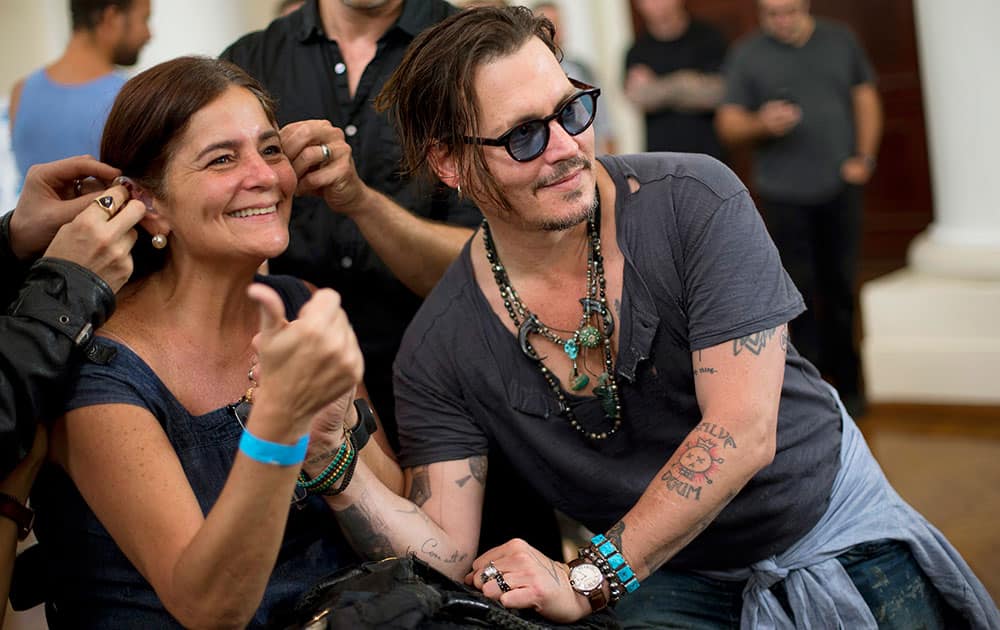 American actor Johnny Depp poses for a photo with a woman that is receiving hearing devices in Rio de Janeiro, Brazil.