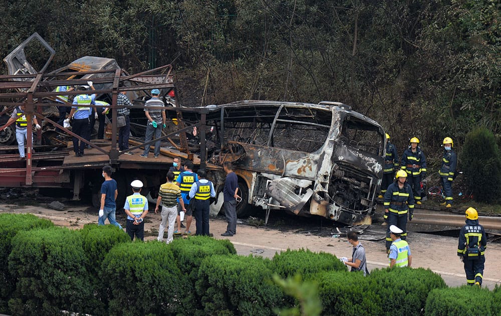 In this photo provided by China's Xinhua News Agency, rescuers work at the site of a highway accident in central China's Hunan Province. The government in Hunan province said in a statement that a flatbed truck lost control and veered into opposite lanes of traffic while dragging a smaller truck driving in the same direction. The trucks collided with an oncoming coach bus and a van, causing a fire, the statement said.