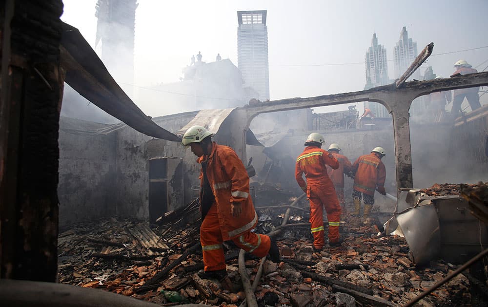 Indonesian firefighters work to extinguish a fire that razes through a slum area in Jakarta, Indonesia.