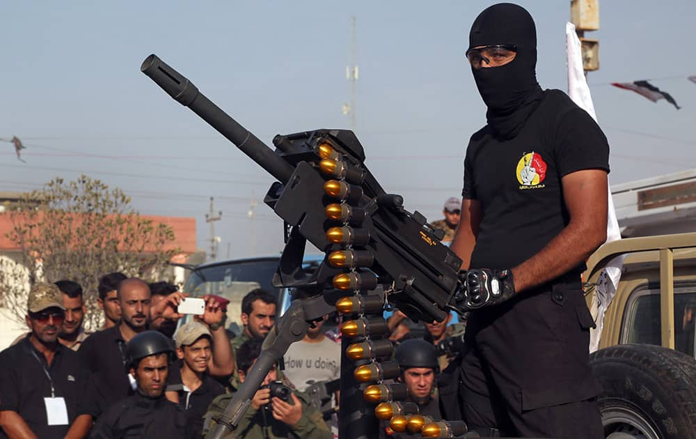 A members of the Abbas combat squad, a Shiite militia group, wearing a shirt with the group's logo, mans a gun atop a vehicle during a military parade in Basra, 340 miles (550 kilometers) southeast of Baghdad, Iraq.