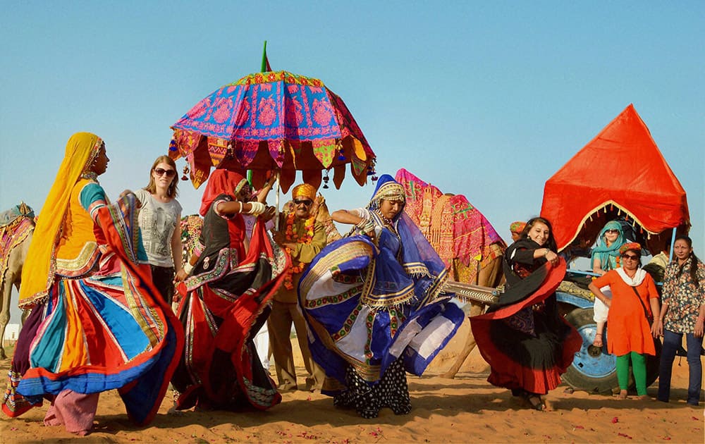 Foreign tourists dance with local artists on the occasion of World Tourism Day in Pushkar.