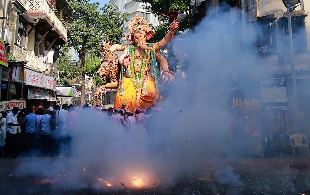 People light firecrackers as an idol of elephant-headed Hindu god Ganesha is taken through the streets prior to its immersion in the Arabian Sea in Mumbai.