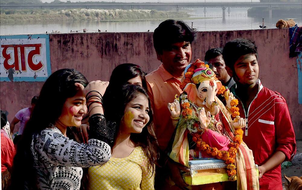 Devotees perform during the Ganesh Visarjan at the banks of Yamuna river in New Delhi.