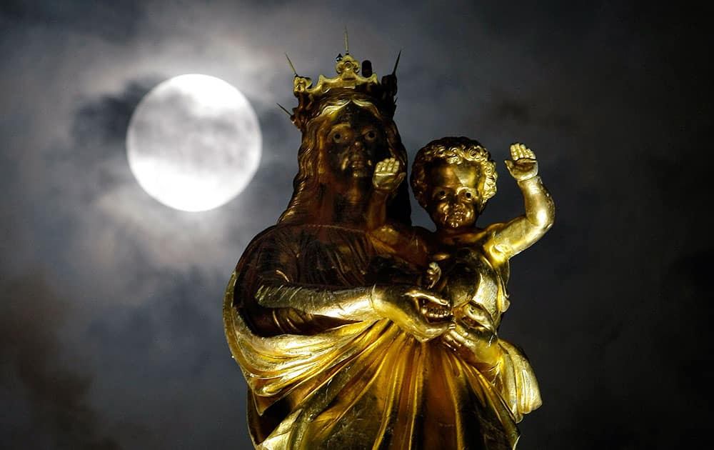 A super moon pasts behind a statue of the Virgin Mary and the Child at Notre Dame de La Garde basilica, before a total lunar eclipse, in Marseille, southern France.
