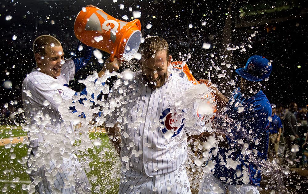 Chicago Cubs Chris Denorfia has water dumped on him by teammates Anthony Rizzo, left, and Dexter Fowler, right, after a walk-off home run against the Kansas City Royals during the 11th inning of a baseball game in Chicago.