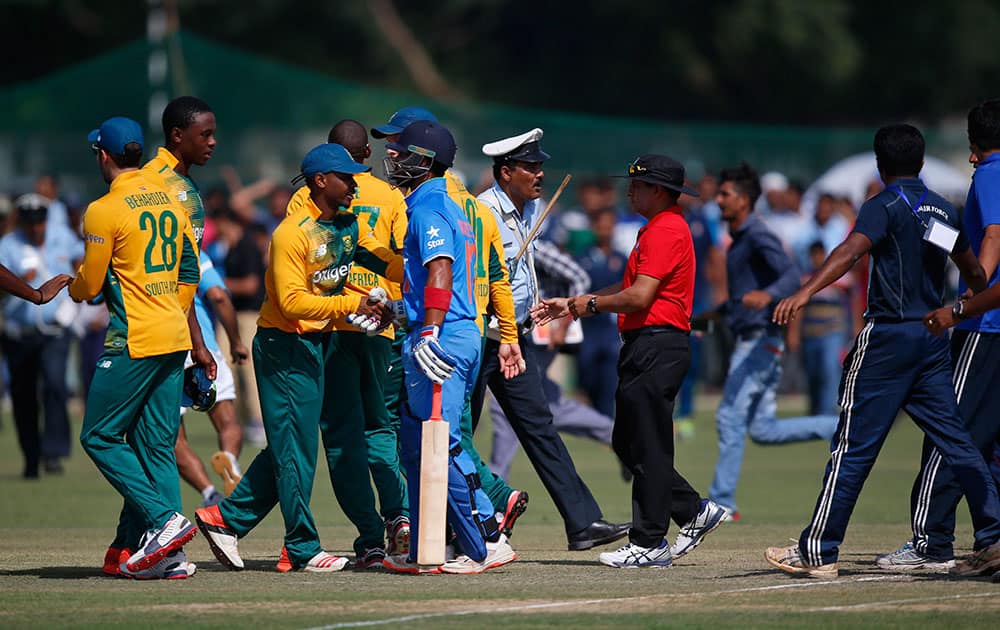 A policeman tries to secure the players after spectators invaded the pitch at the end of a practice Twenty20 match between South Africa and India A team in New Delhi.