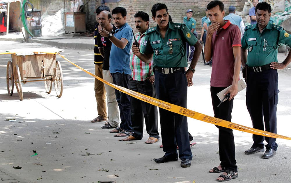 Members of Bangladeshi police and detective branch stand by the site where Italian citizen Cesare Tavella was gunned down by unidentified assailants in Dhaka, Bangladesh.