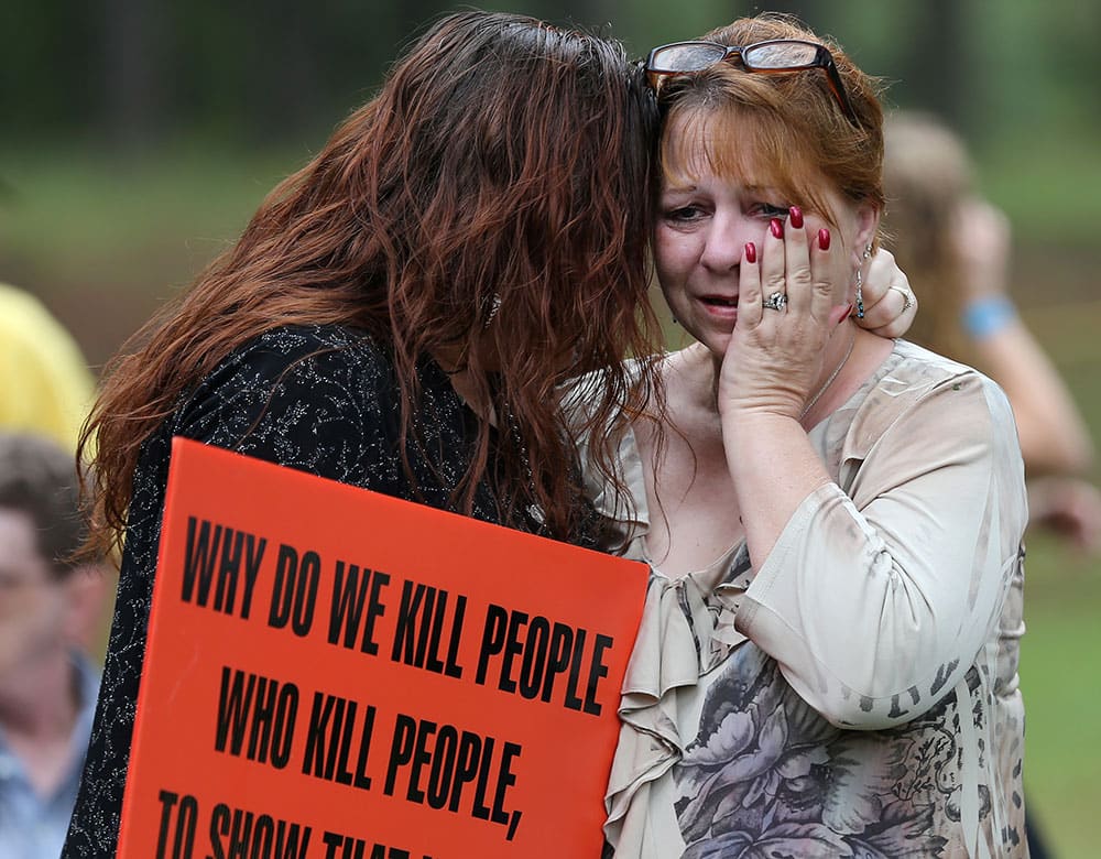 Dawn Skorcik, left, of Marietta, Ga., and Dawn Barber, of Powder Springs, Ga., comfort each other while protesting outside of Georgia Diagnostic Prison in Jackson, Ga.