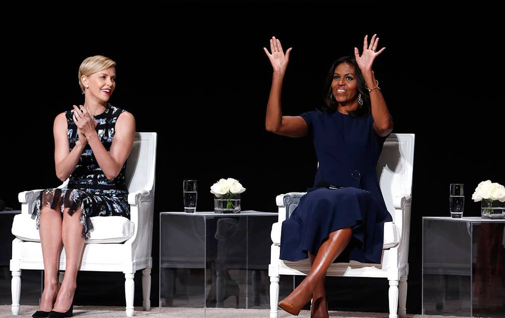 Actress Charlize Theron, left, applauds first lady Michelle Obama as she takes the stage for a panel discussion entitled 