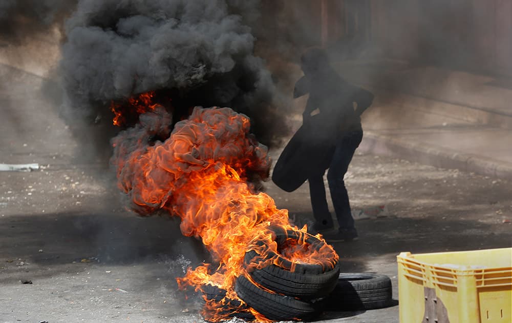 A Palestinian youth sets tires on fire during clashes with Israeli soldiers in the West Bank city of Hebron.