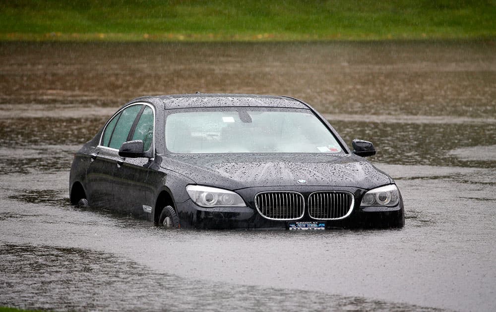 A vehicle is stranded on a flooded driveway leading to a shopping plaza in Guilderland, N.Y. The National Weather Service has issued flood watches for much of the eastern half of upstate New York as a storm dumps more than two inches of rain across the region.