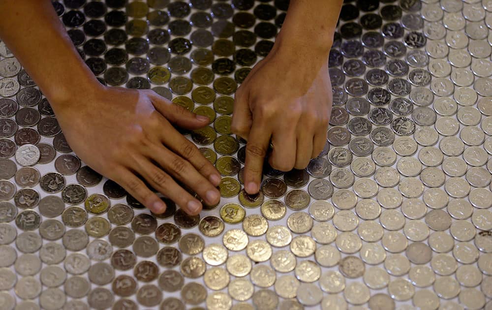 An employee of an international money remittance company arranges coins in an attempt to set a new Guinness world record for the largest coin mosaic at suburban Quezon city northeast of Manila, Philippines.