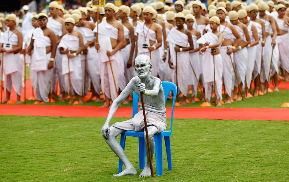 Shri Gopal, a Gandhian or follower of Gandhi's philosophy, sits dressed as India’s independence leader Mahatma Gandhi, as he is joined by school children also dressed as Gandhi in an attempt to create a Guinness record, during celebrations to mark Gandhi’s birth anniversary in Bangalore.