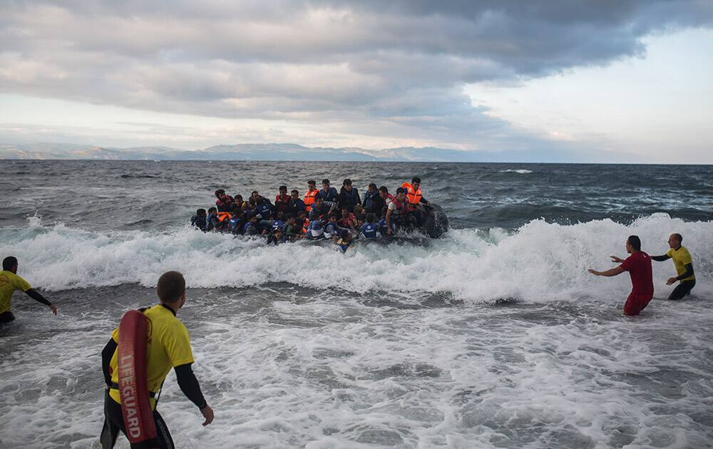 Four lifeguards from Barcelona, Spain, working as volunteers, help a disembarking dinghy as refugees arrive from the Turkish coasts to the northeastern Greek island of Lesbos.