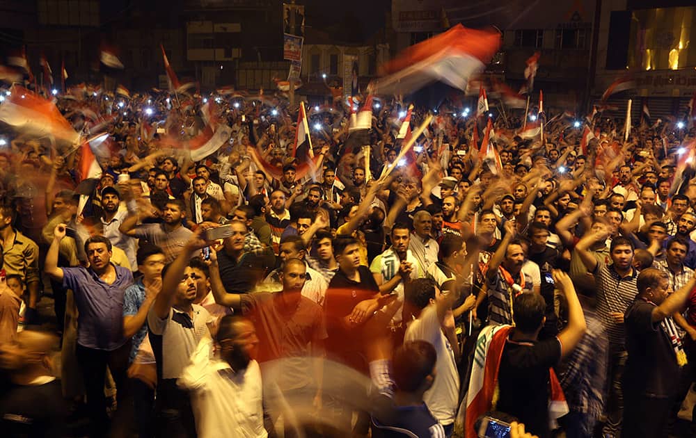 Iraqi protesters chant slogans as they wave national flags during a demonstration against corruption in Tahrir Square in Baghdad.