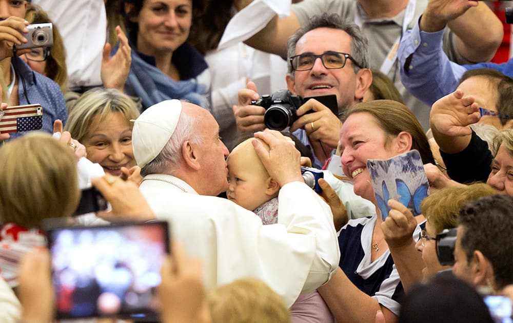 Pope Francis kisses a child as he arrives for an audience with members of the Italian Food Bank Network charity organization in the Paul VI hall at the Vatican.