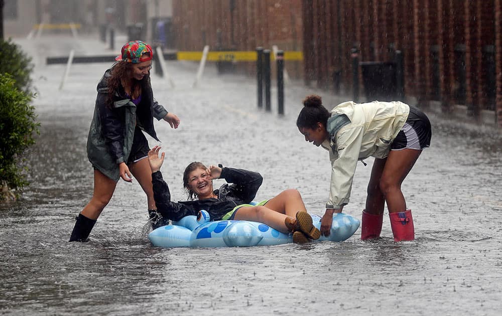 Anna Wilson laughs as she plays with friends Madi Kois, left, and Wesli Jones on a flooded street in Charleston, S.C.