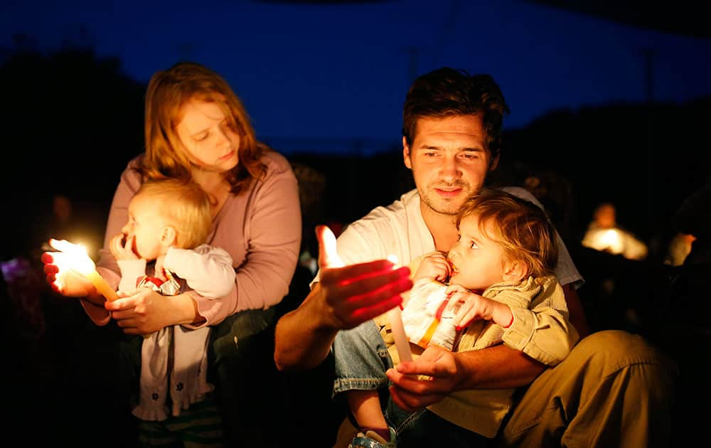 Kyle Workman holds his daughter Samantha Workman while sitting beside his wife Christina Workman who is holding their daughter Pepper Workman during a prayer vigil in Winston.