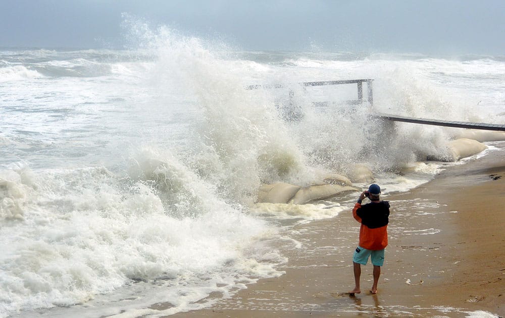 Ty Luckette of Buxton photographs waves pounding the shoreline behind the hotels at the north end of the town on North Carolina's Hatteras Island during high tide.