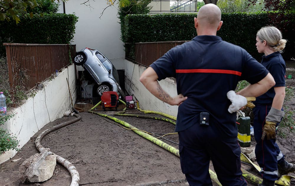 Rescue workers watch a car stuck in the entrance of an underground garage in Mandelieu la Napoule, southern France. In a matter of minutes, torrential rains transformed the postcard-perfect French Riviera into a terrifying flood zone, leaving more than a dozen of deads, trapping hundreds of ailing pilgrims and halting car and train traffic Sunday along the mud-drenched Mediterranean coast.