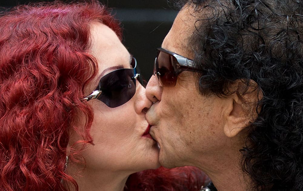 El Tri lead singer Alex Lora, right, kisses his wife and bandmember Chela Lora as they pose for pictures during a press conference to announce the release of the band's new album, 