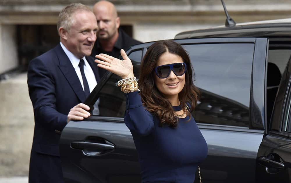 Mexican actress Salma Hayek waves while her husband Francois-Henri Pinault, CEO of luxury group Kering, holds the car door after Stella McCartneys spring-summer 2016 ready-to-wear fashion collection presented during the Paris Fashion Week.