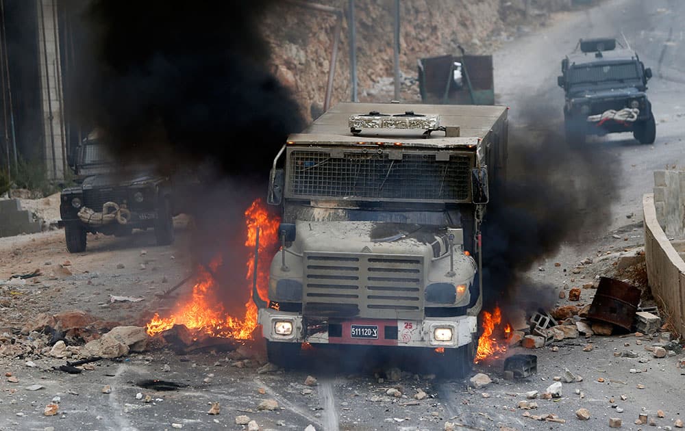 An Israeli military vehicle drives through burning tires during a raid in the West Bank city of Nablus.