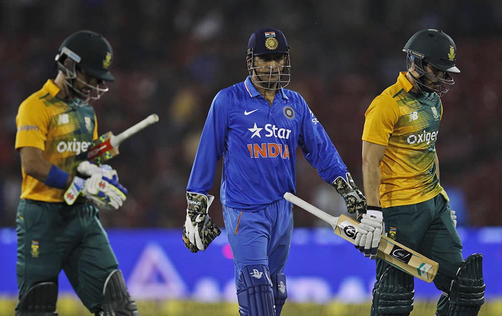 South African batsmen Farhaan Behardien, Jean-Paul Duminy and Indian captain Mahendra Singh Dhoni walk back as their second Twenty20 cricket match is disrupted after spectators threw bottles in Cuttack.