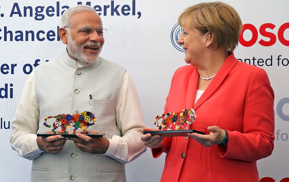 German Chancellor, Angela Merkel and Indian Prime Minister Narendra Modi smile after receiving souvenirs depicting the logo of 'Make in India' campaign during their visit to German engineering company Bosch's vocational centre in Bangalore.