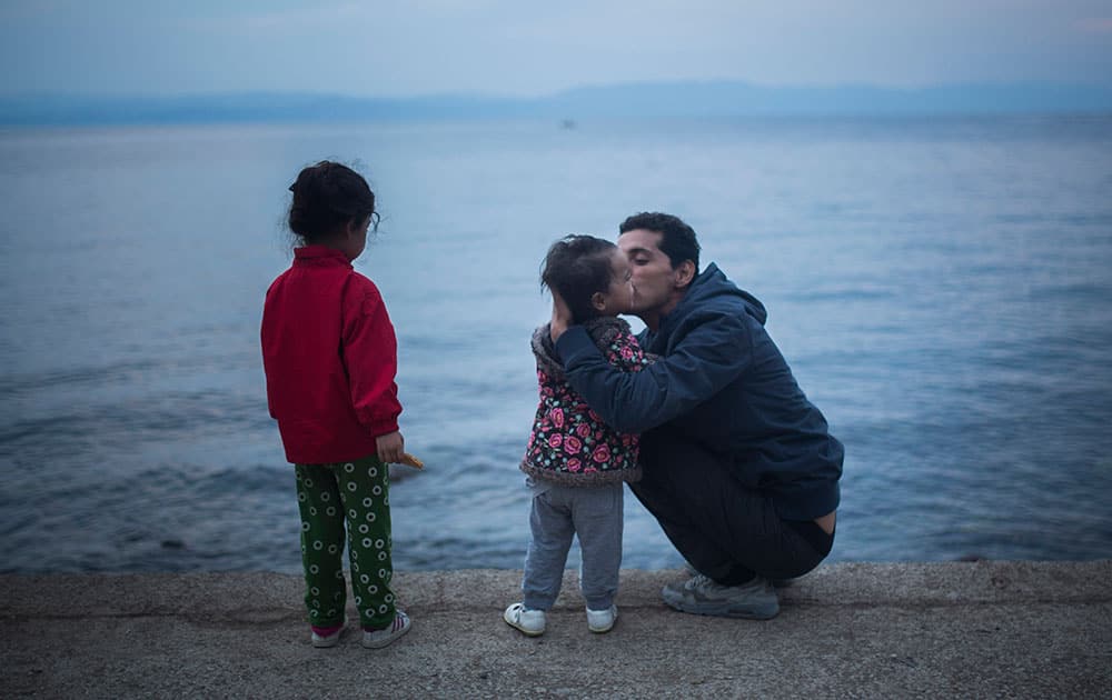 A man kisses a child at the seaside of Lesbos island, after they spent a night at a resting point with other refugees that crossed from Turkey to Greece, on Lesbos island , Greece.