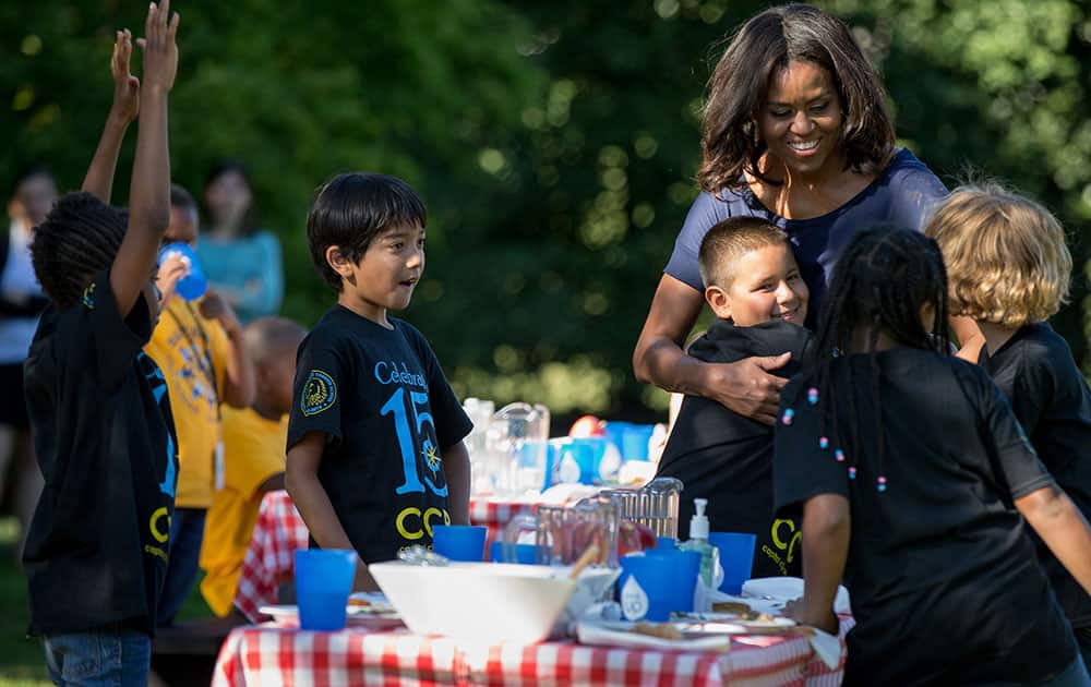 First lady Michelle Obama hugs school children from Washington area as they eat together on the South Lawn of the White House in Washington.
